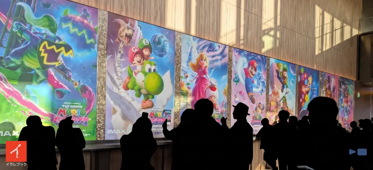 映画「ザ・スーパーマリオギャラクシー・ムービー」の劇場壁面ポスターを鑑賞する入場者たち
